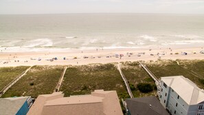 A beach view with a boardwalk leading to the shore, sandy beach, and ocean.