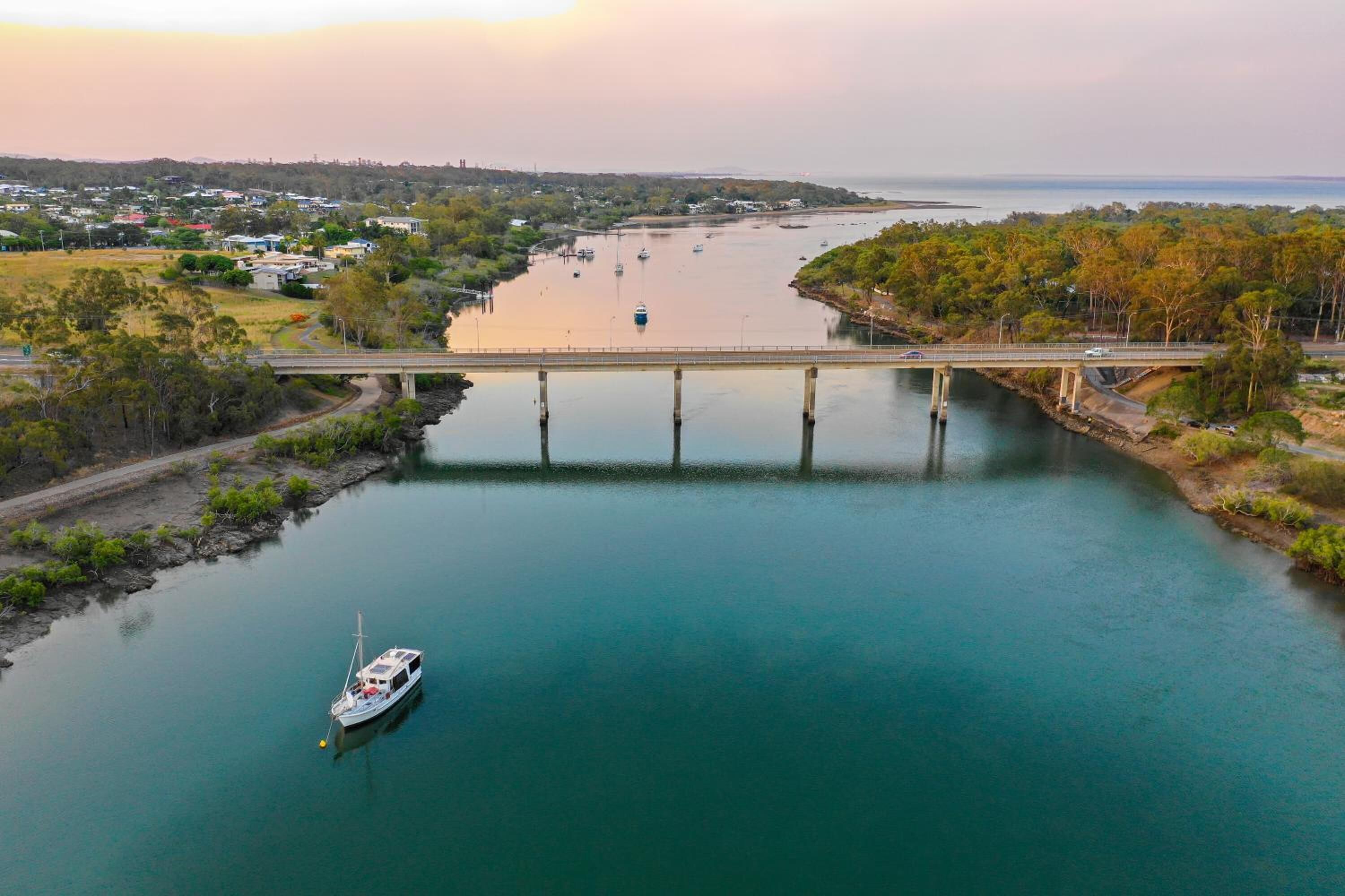 Une rivière avec un pont, un bateau et une ville en arrière-plan.