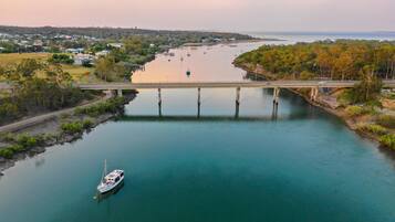 Une rivière avec un pont, un bateau et une ville en arrière-plan.