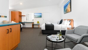 Habitación de hotel con cama, escritorio, kitchenette y zona de estar.