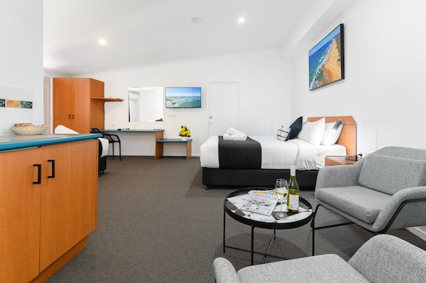 A hotel room with a bed, a desk, a kitchenette, and a seating area. - CQ Motel Gladstone (Gladstone)