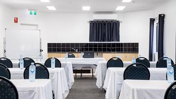 A conference room with tables, chairs, a whiteboard, and an air conditioning unit.