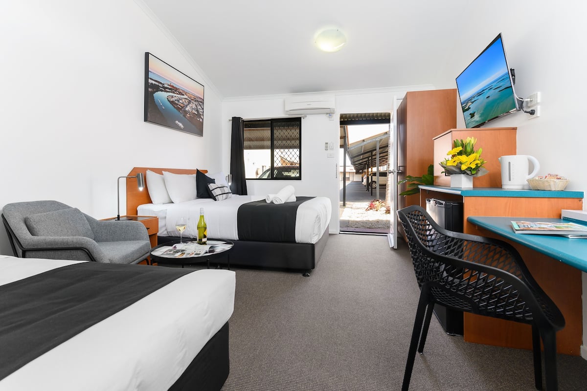 A hotel room with a bed, a desk, a chair, a TV, and a window.