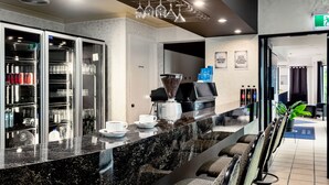 Un moderno hall de hotel con mostrador de recepción de mármol, zona de estar y una máquina de café.