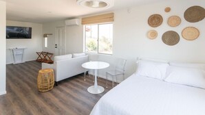 Une chambre d’hôtel moderne avec un grand lit, un canapé, une petite table et un téléviseur.