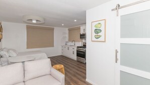 Un salon moderne avec un canapé, une table à manger et une cuisine en arrière-plan.