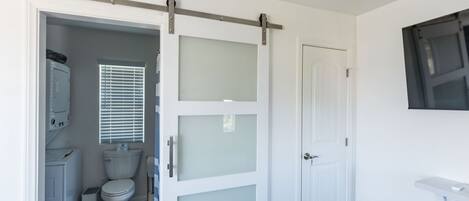 A bathroom with a toilet, a cabinet, and a window with blinds.