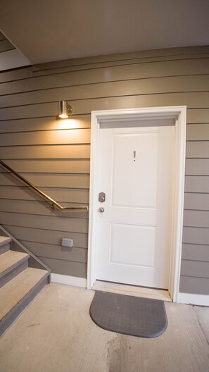 Enter through the welcoming white door, flanked by a metal handrail and stairs.