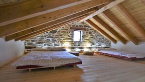 Quarto de sótão acolhedor com duas camas, uma parede de pedra e vigas de madeira.