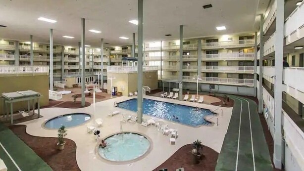 Un hôtel à plusieurs étages doté d’une piscine centrale, de nombreux balcons et d’espaces de détente en plein air.