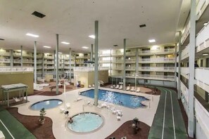 Ein Hotel mit mehreren Ebenen, einem zentralen Schwimmbad, zahlreichen Balkonen und Außenbereich-Sitzgelegenheiten.