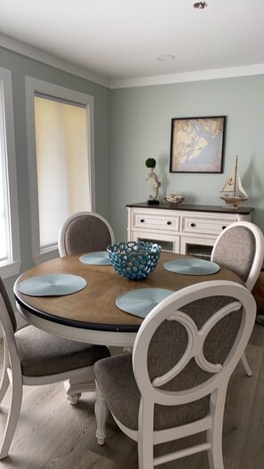Une salle à manger avec une table ronde, des chaises blanches et un vase décoratif.