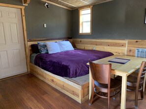 Cozy cabin-style room with a comfortable bed, small table, and chair.