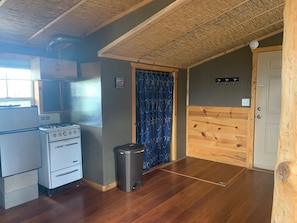 Functional kitchen area with gas stove, oven, and trash bin for a convenient cooking space.