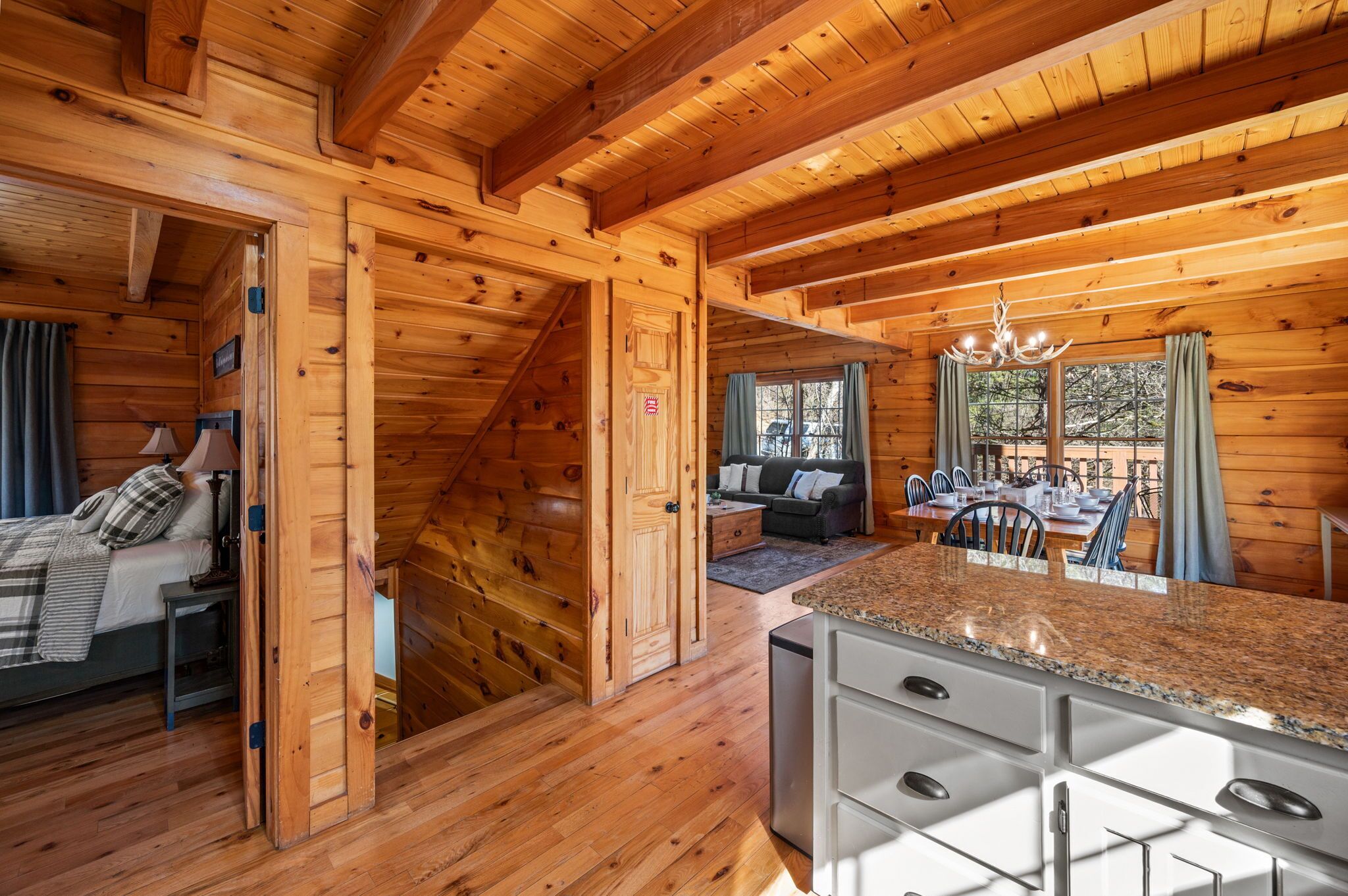 L’intérieur d’un chalet en bois comprend un coin repas, une cuisine et une chambre avec un lit et une table de chevet.