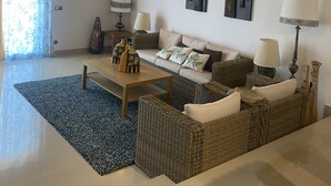 Een woonkamer met een houten plafond, een bank, een salontafel en een lamp.