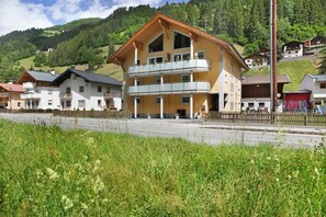 Ein mehrstöckiges Gebäude mit Balkonen, einer roten Garage und einer Bergkulisse im Hintergrund.