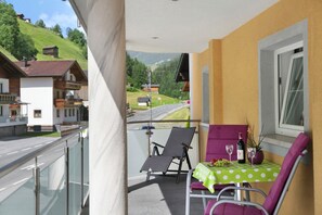 Ein Balkon mit Tisch, Stühlen und Blick auf eine Straße und Gebäude.