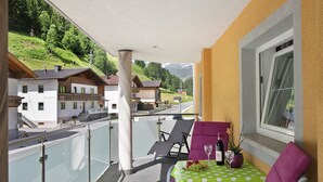 A balcony with a table, chairs, and a view of houses and mountains. - Apartment 'Bergglück' with Mountain View, Balcony and Wi-Fi (See)