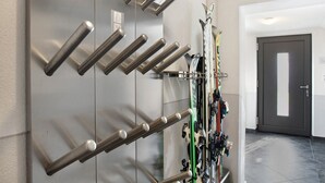 A wall-mounted ski rack with skis and poles, a door, and a tiled floor. - Apartment 'Bergglück' with Mountain View, Balcony and Wi-Fi (See)
