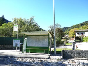 A bus stop with a bench, a sign, and a stone wall. - Chalet Al Portic by Interhome (Olivone)