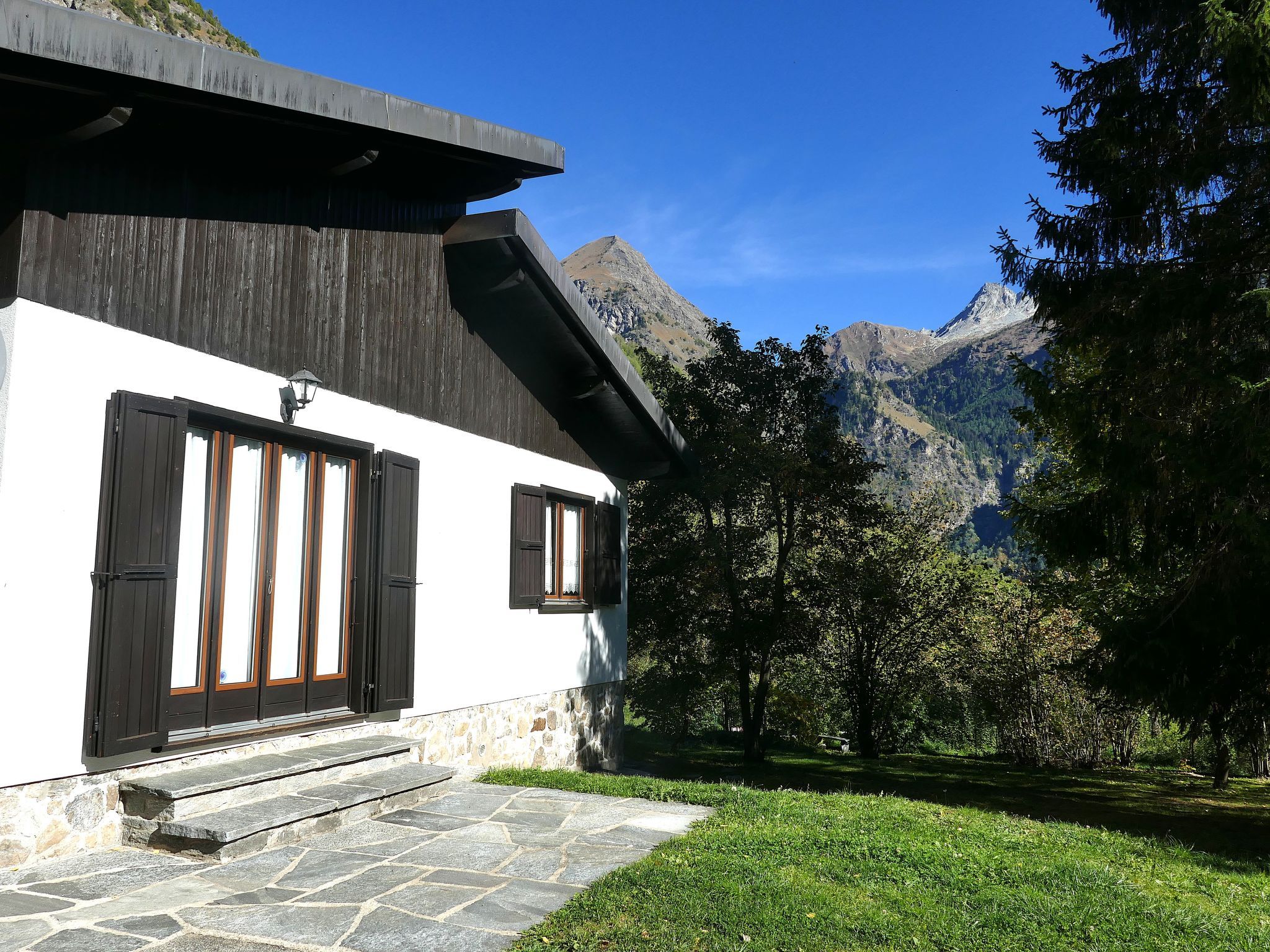 A modern building with a stone facade, large windows, and a view of a mountainous landscape.