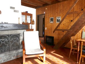 A wooden interior with a chair, a fireplace, and a staircase. - Chalet Al Portic by Interhome (Olivone)