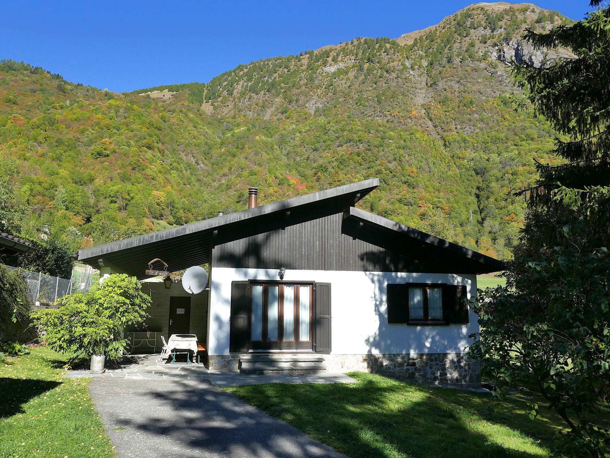 Ett modernt hus med ett sluttande tak, en satellitmottagare och en grund av sten.