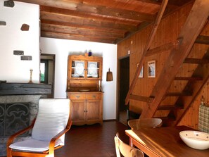 A rustic interior with a wooden staircase, a dining table, a chair, and a cabinet with glass doors. - Chalet Al Portic by Interhome (Olivone)