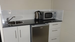 A compact kitchen with a stainless steel sink, a microwave, and a refrigerator. - Balranald Club Motel (Balranald)