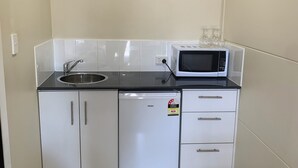 A compact kitchen with a sink, microwave, refrigerator, and cabinets. - Balranald Club Motel (Balranald)