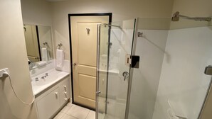 A bathroom with a glass-enclosed shower, a white sink, and a mirror. - Balranald Club Motel (Balranald)