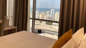 A hotel room with a large bed, a desk, and a view of a cityscape and water.