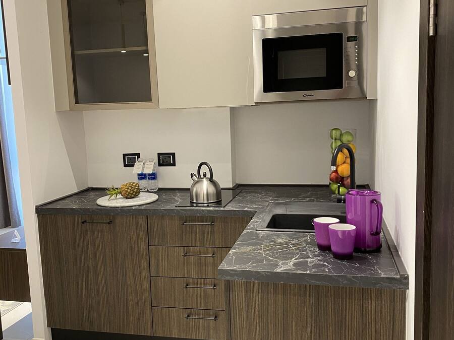 A modern kitchen with a microwave, a kettle, and a fruit bowl.