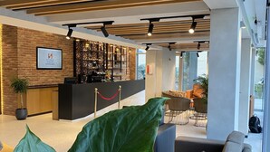 A modern lobby with a reception desk, seating area, and large windows.