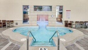 Een zwembadgedeelte met een jacuzzi, zitplaatsen en een klok aan de muur.