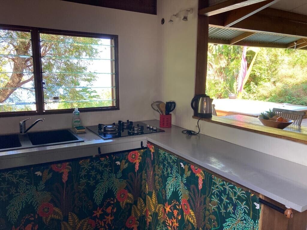 A kitchen with a sink, stove, and window overlooking greenery.