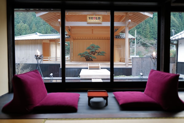 A traditional Japanese room with tatami flooring, a low wooden table, and two red cushions.