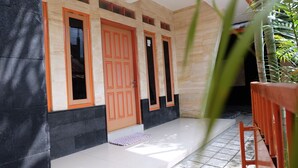 A building facade with three doors, a tiled entrance, and a wooden railing. - Homestay Simply Homy Unit Gembiraloka (Yogyakarta)