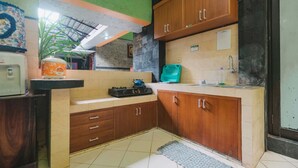 A kitchen with wooden cabinets, a gas stove, and a sink. - Homestay Simply Homy Unit Gembiraloka (Yogyakarta)