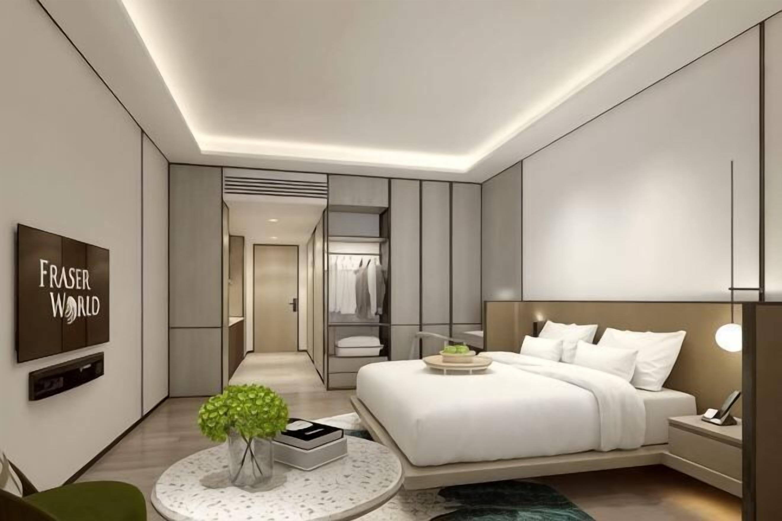 A modern hotel room with a large bed, a round coffee table, and a TV mounted on the wall.