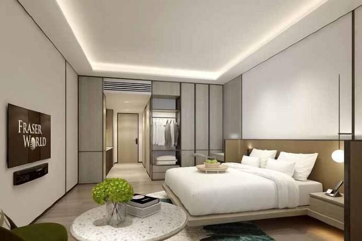 A modern hotel room with a bed, bedside table, and a round table with a vase.