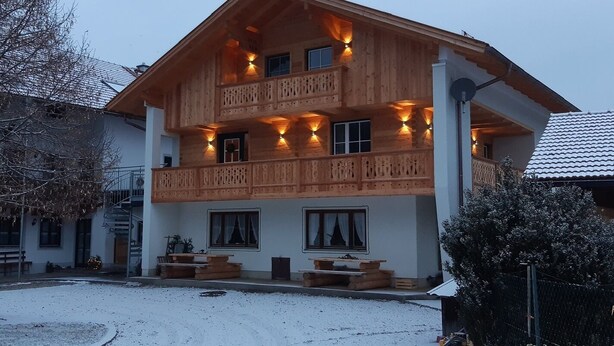 Un chalet in legno a due piani con balconi e area salotto esterna.