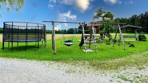 Un'area giochi con trampolino, altalene e struttura per arrampicata.