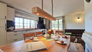 Una cucina moderna con un tavolo da pranzo in legno apparecchiato, un divano e un cane.