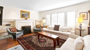 Amplia sala de estar con chimenea, un sofá, sillones y una mesa de centro.