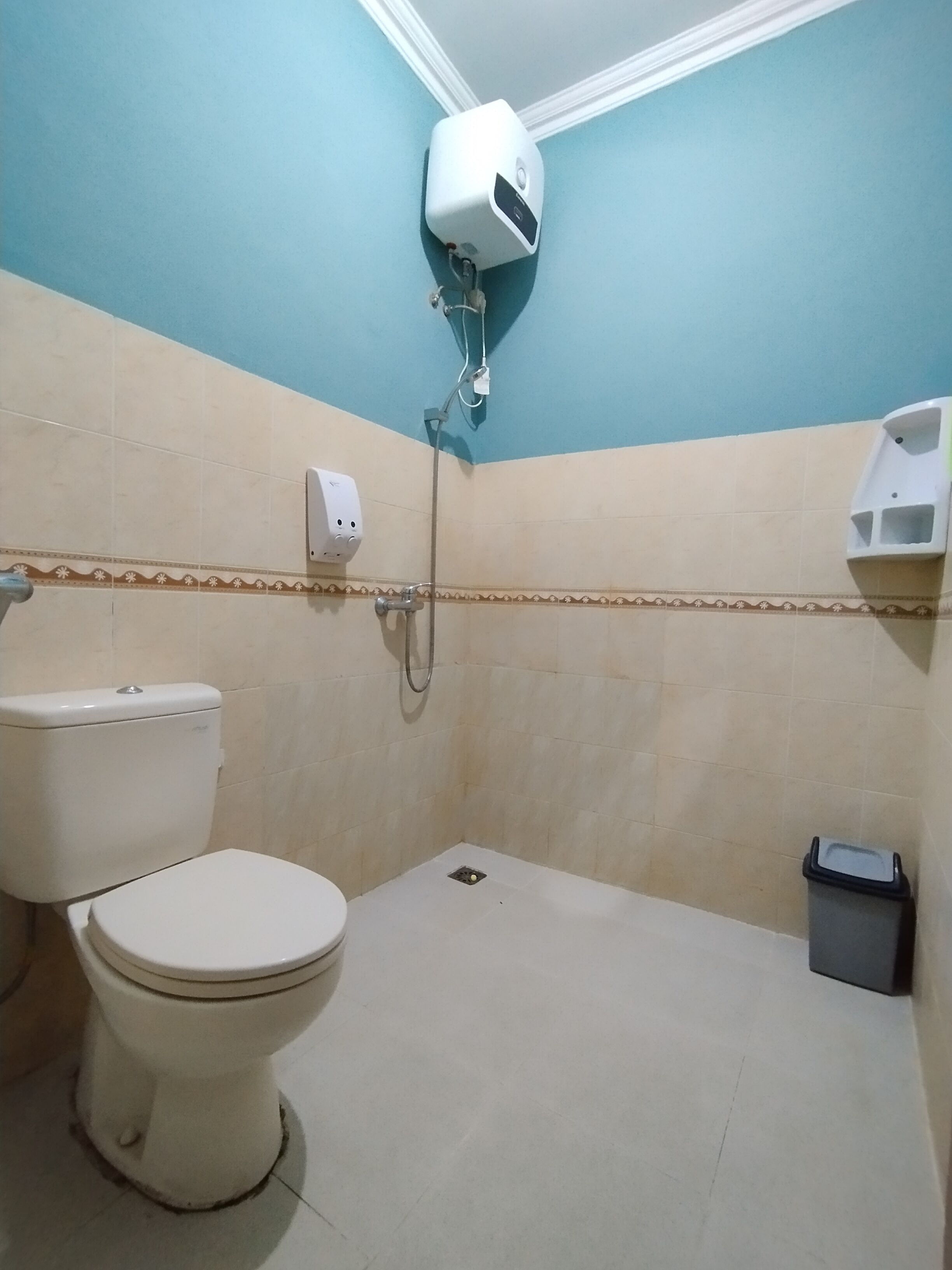 A small bathroom with a toilet, a shower, and a trash bin.