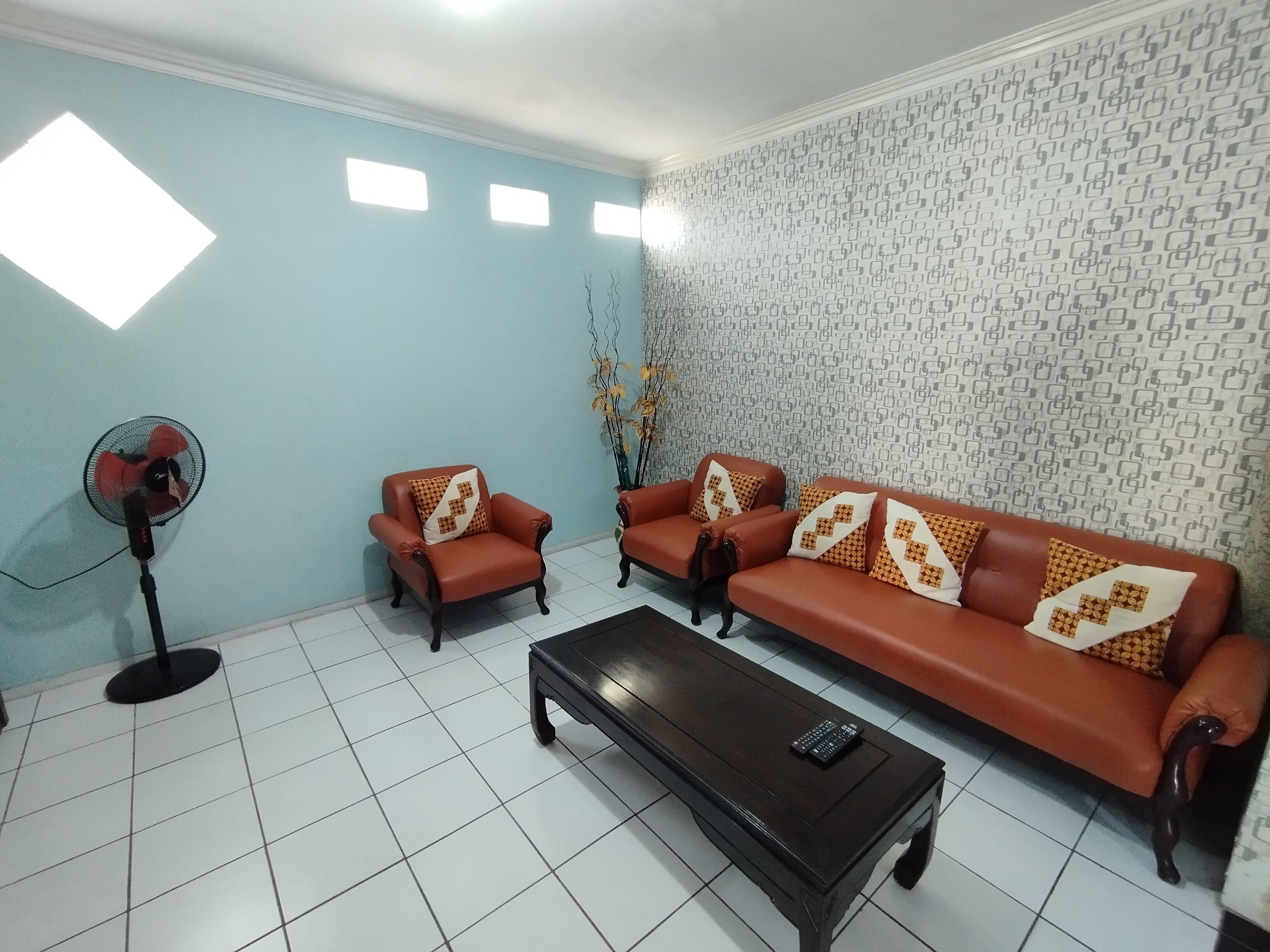 Una sala de estar con un sofá, una mesa de centro y un ventilador de pie.