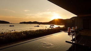 A sunset view from a modern building with a pool extending to the water, overlooking a calm sea with rocks and distant land. - Fairfield by Marriott Wakayama Kumano Kodo Susami (Susami)