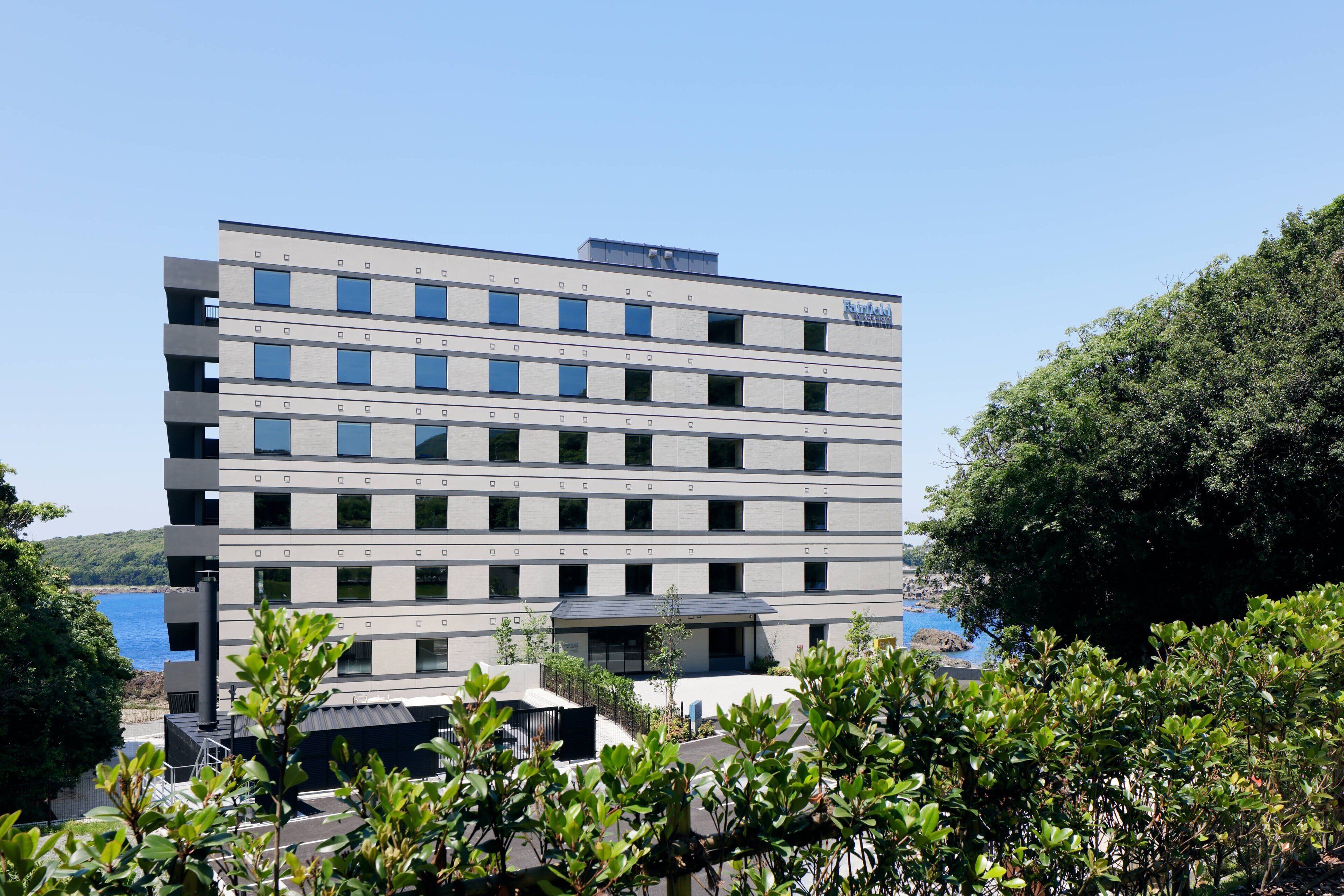 Un hotel de varios pisos con un diseño arquitectónico moderno, que presenta un techo plano y una serie de ventanas en cada planta.